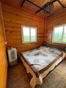 ein Schlafzimmer mit einem Bett in einer Holzhütte in der Unterkunft Elevated Serenity Lodge in Khao Kho in Khao Kho