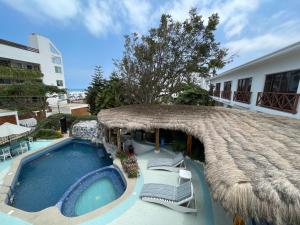 a swimming pool with chairs and a thatch umbrella at Hosteria Punta Blanca in Punta Blanca