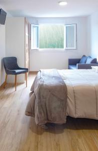ein Schlafzimmer mit einem Bett, einem Stuhl und einem Fenster in der Unterkunft AG Casa Anema 10 huéspedes a 2km de la playa Razo in A Coruña