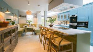 una cocina con armarios azules y un bar con sillas en The Papered House, en Beaumaris