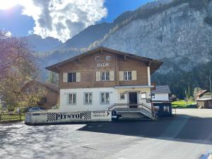 a large wooden building in front of a mountain at Pension Balm in Meiringen