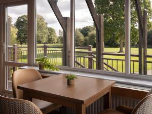 Delta Hotels by Marriott Tudor Park Country Club في ميدستون: طاولة وكراسي في غرفة بها نوافذ