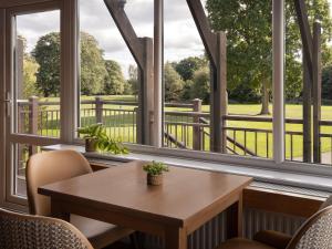a table and chairs in a room with windows at Delta Hotels by Marriott Tudor Park Country Club in Maidstone