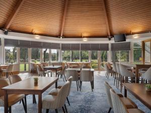 un restaurant avec des tables, des chaises et des fenêtres dans l'établissement Delta Hotels by Marriott Tudor Park Country Club, à Maidstone