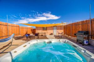 a hot tub on a patio with a grill at Cacti Sanctuary in Sunfair Heights
