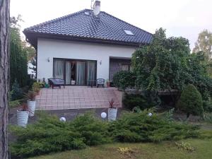 a small white house with a patio in a yard at Dom całoroczny na wynajem - Zalesie nad jeziorem Chełmżyńskim koło Torunia 