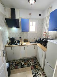 małą kuchnię z niebieskimi szafkami i zlewem w obiekcie Appartement S+2 à lac 1 à côté hôtel Movempick w mieście Tunis