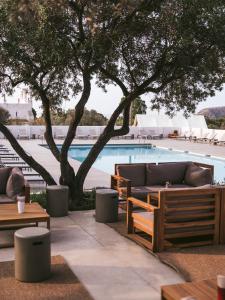 uma piscina com sofás, mesas e árvores em wecamp Cadaqués em Cadaqués