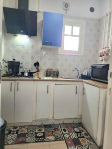 małą kuchnię z białymi szafkami i niebieską szafką w obiekcie Appartement S+2 à lac 1 à côté hôtel Movempick w mieście Tunis