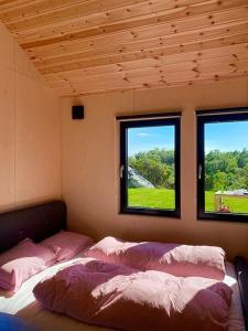 a bedroom with two beds and two windows at Hytte til leie i Ryfylke in Hjelmeland