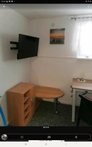 a room with a desk and a television on a wall at Gästezimmer Neumann in Bad Münder am Deister