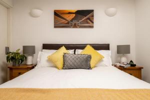 a bedroom with a white bed with yellow pillows at Bulverton House Holiday Cottages in Sidmouth