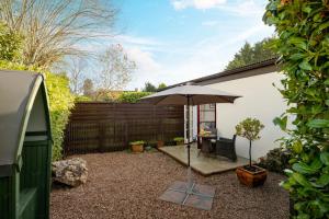a patio with an umbrella and a table and chairs at Bulverton House Holiday Cottages in Sidmouth