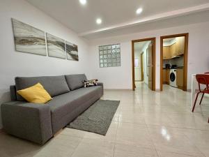 a living room with a gray couch and a kitchen at Little Horse apartments 3 in Tarragona