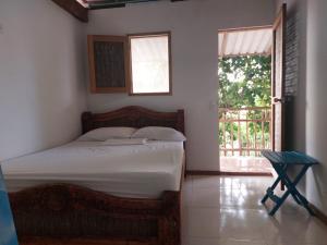 a bedroom with a bed and a window and a chair at Hostal El Nido del Azulejo in Barú