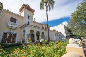 a building with a palm tree and flowers at Augusta Palace in Salta