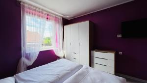 a bedroom with purple walls and a bed and a window at Apartment Am Paradies in Bad Lauterberg