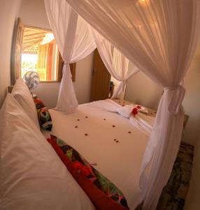 a bedroom with two beds with white curtains at Pousada Vila Jasmim em Caraíva in Caraíva