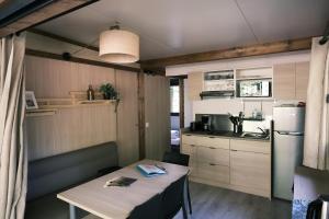 a small kitchen with a table and a refrigerator at Lodge avec SPA privatif - Foret et Lac in Liginiac