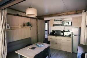 uma pequena cozinha com uma mesa e um frigorífico em Lodge avec SPA privatif - Foret et Lac em Liginiac