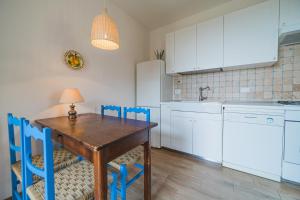 una cocina con armarios blancos y una mesa y sillas de madera. en Casa al Mare, en Capoliveri