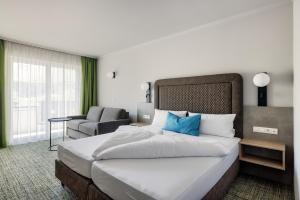 オーバーグルグルにあるAlpenaussichtの大きなベッドと椅子が備わるホテルルームです。