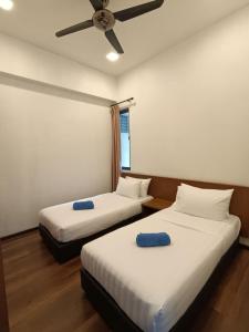 two beds in a room with a ceiling fan at The Retreat Sweety 3BR H/Stay in Brinchang