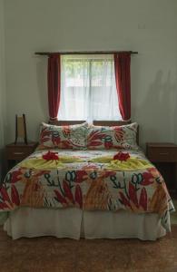 a bedroom with a bed with a red curtain and a window at Hostal y Cabañas Aorangi in Hanga Roa