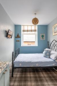 a bedroom with a bed with blue walls and a window at Beach Snug in Lytham St Annes