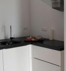 a kitchen with white cabinets and a black counter top at Sroom Metzingen in Metzingen