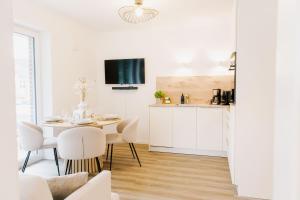 a white kitchen and dining room with a table and chairs at Küsten Suite de See - Suite 1 direkte Deichlage, Terrasse, 53qm in Greetsiel