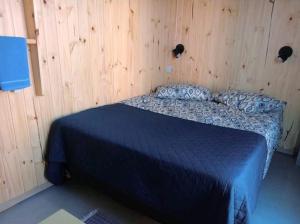 a bedroom with a blue bed in a wooden wall at Quarto Privativo em Santana de Parnaiba 02 in Santana de Parnaíba