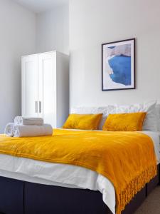 a bedroom with a large bed with a yellow blanket at Palatial Six Bedroom Haven in Northampton