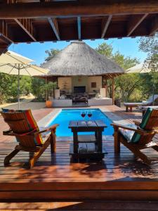 a deck with chairs and a table and a swimming pool at The Dreamcatcher Lodge in Hoedspruit