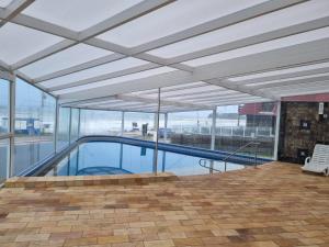 a swimming pool in a building with glass windows at Dunas Praia Hotel in Torres
