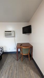 a room with a desk and a television and a table at Portland Value Inn in Portland