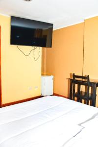 a bedroom with a bed with a tv on the wall at Hotel Santa Ana in Ayacucho