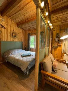 - une chambre avec un lit dans une cabane en bois dans l'établissement Cabane de charme en pleine forêt - Domaine Temali, à Labouheyre