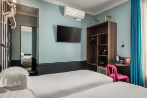 um quarto de hotel com duas camas e uma televisão em Hotel Archetype Etoile em Paris