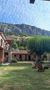 une cour avec bancs et une maison avec une montagne en arrière-plan dans l'établissement Theopetra, à Theópetra