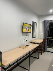 Habitación con escritorio y TV en la pared. en โรงแรมนิยม เอสทีเอ็น 2 - Niyom STN 2 Hotel, en Ban Phue