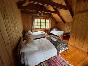 a bedroom with two beds in a wooden cabin at Green Baker Lodge in Puerto Bertrand