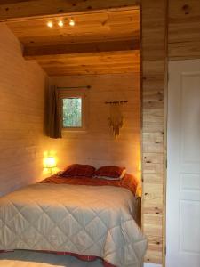 een slaapkamer met een bed in een blokhut bij Cabane au milieu des pins - Domaine Temali in Labouheyre