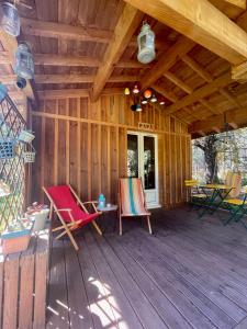 une véranda dans une cabane en bois avec deux chaises et une table dans l'établissement Cabane au milieu des pins - Domaine Temali, à Labouheyre