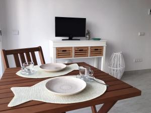 un tavolo da pranzo con 2 piatti e una TV di Apartamentos Roca Plana - Formentera Break a Es Pujols