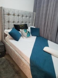 a bed with blue pillows and a blue blanket at Pangani Oasis Gem 2-BR Stylish Apartment in Nairobi