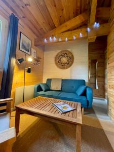 - un salon avec un canapé bleu et une table basse dans l'établissement Cabane au milieu des pins - Domaine Temali, à Labouheyre