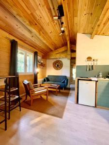 Elle comprend un salon doté de plafonds en bois et d'un canapé bleu. dans l'établissement Cabane au milieu des pins - Domaine Temali, à Labouheyre