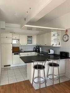 cocina con armarios blancos y encimera negra en Ferienwohnung Sellin, en Ostseebad Sellin