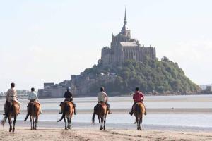 um grupo de pessoas andando a cavalo na praia em Auberge de Jeunesse HI Genêts em Genêts